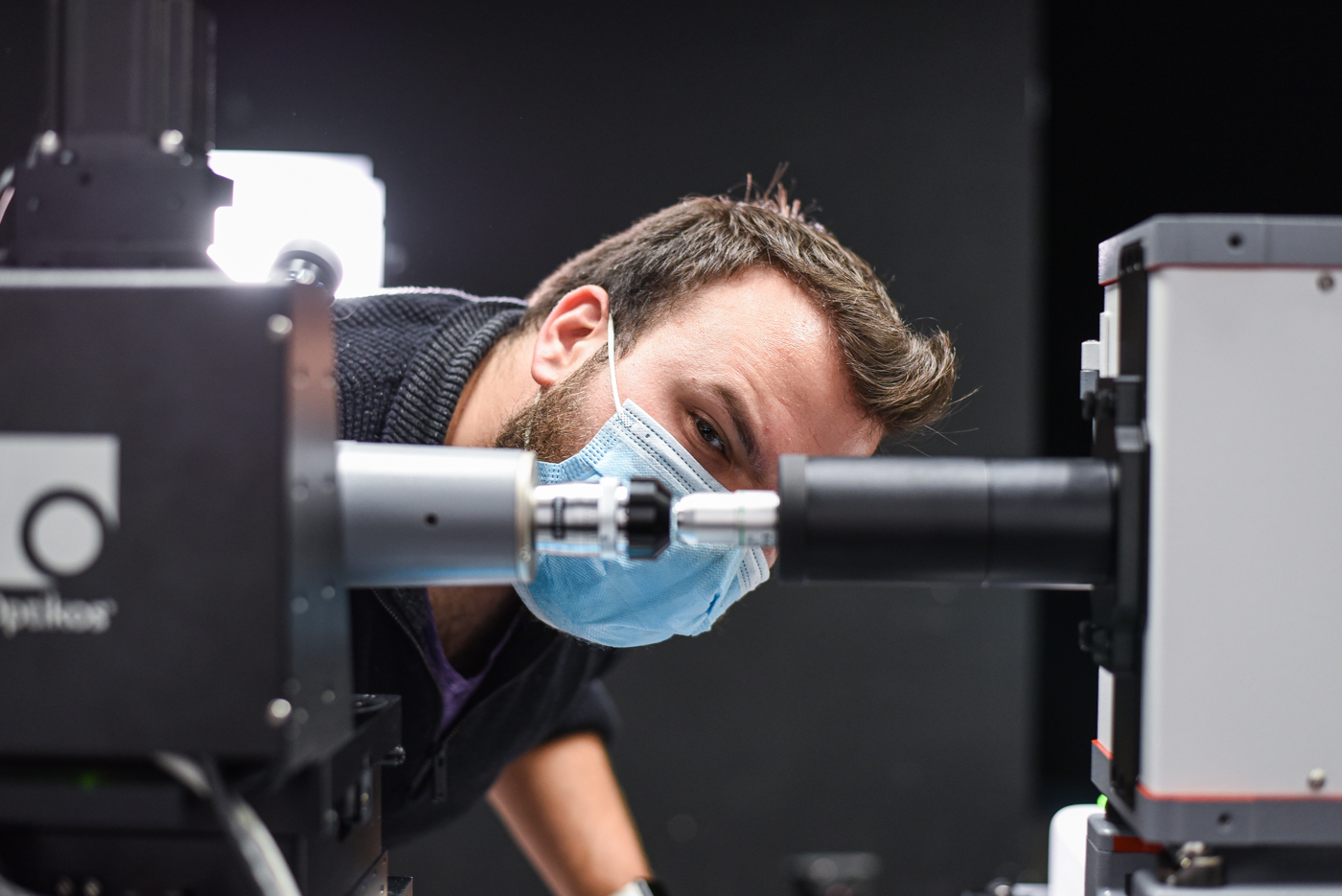 Engineer peers between equipment in testing laboratory.